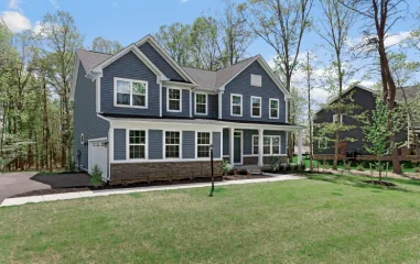 Blue two-story house with white trim and a stone base