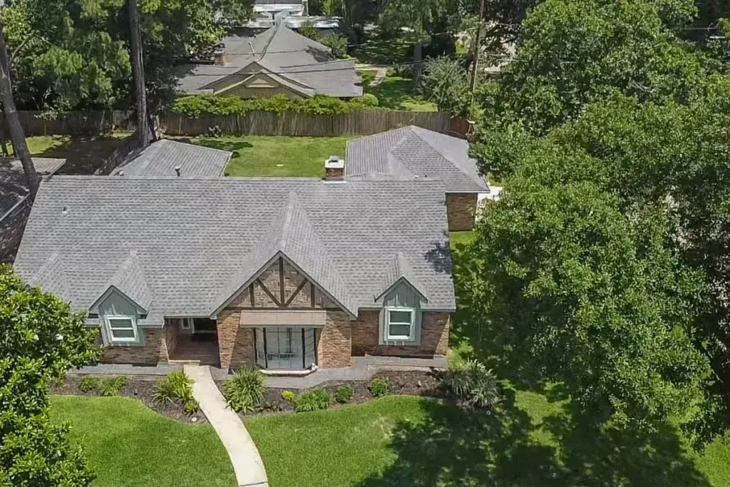Aerial view of a brick house with a gray shingle roof